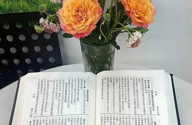 一本打開的聖經放在桌上，旁邊擺著一瓶鮮花，代表每日恩言的靈修時光